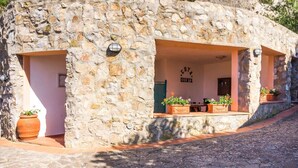 Un bâtiment en pierre doté d’un patio couvert, de plantes en pot et d’une enseigne indiquant « Fonda Quinta ».