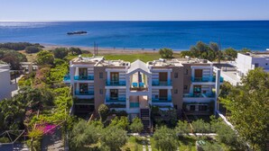 A multi-story hotel with balconies overlooking a beach and the sea. - Holiday home in Kiotari with a barbecue (Kiotari)
