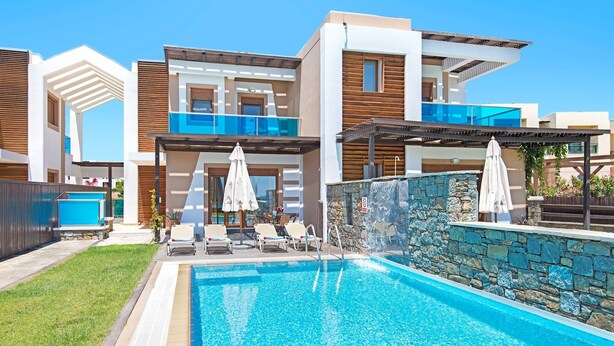 A modern pool area with a clear blue pool, lounge chairs, and umbrellas. - Holiday home in Kiotari with a barbecue (Kiotari)