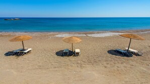 A beach with three sun umbrellas and lounge chairs. - Holiday home in Kiotari with a barbecue (Kiotari)