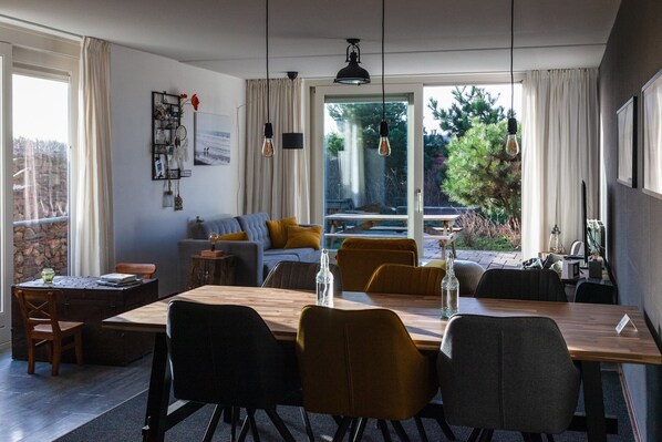 A modern dining area with a wooden table, black and mustard chairs, and pendant lighting.