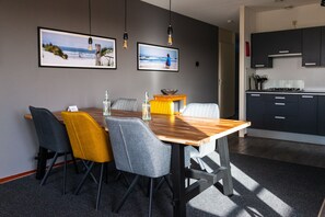 A dining area with a wooden table, grey and yellow chairs, and two framed pictures on the wall.