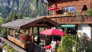 A wooden chalet with a balcony, outdoor seating, and flower boxes. - Alpbach Bergwald Apartments (Alpbach)