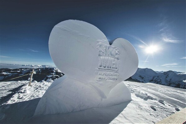 A snow sculpture of a heart with the text "SKI JUEL ALPBACTAL WILDSCHRON" on a snowy mountain slope.