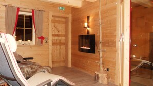 A wooden interior with a fireplace, a sofa, and a chair. - Alpbach Bergwald Apartments (Alpbach)