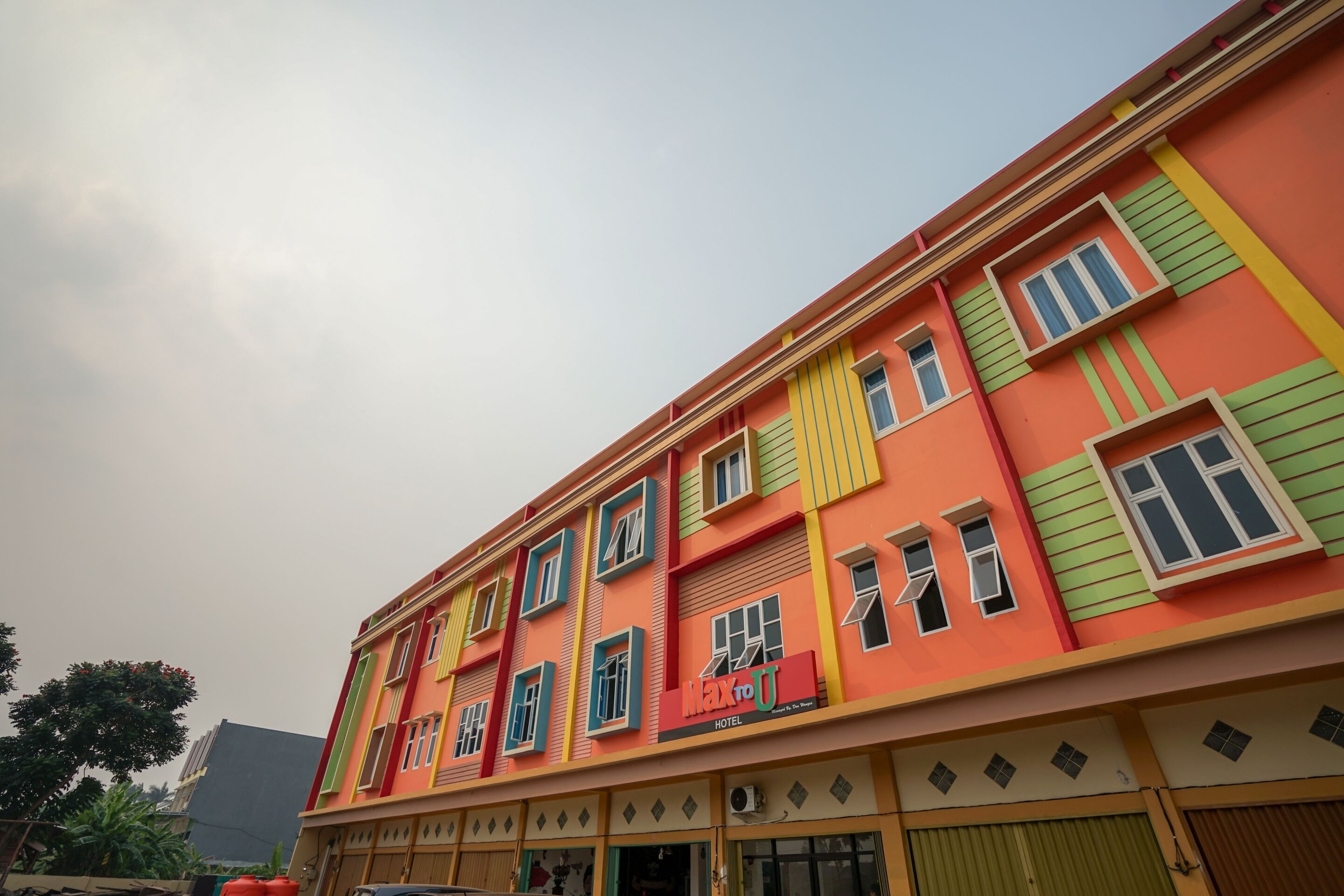 Un edificio de varios pisos con un llamativo letrero que dice "Max to U Hotel".