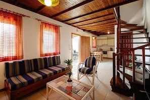 Una sala de estar con un sofá, una silla, una mesa de centro y una escalera.