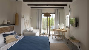 Un dormitorio con una cama grande, un escritorio, una silla y un televisor.