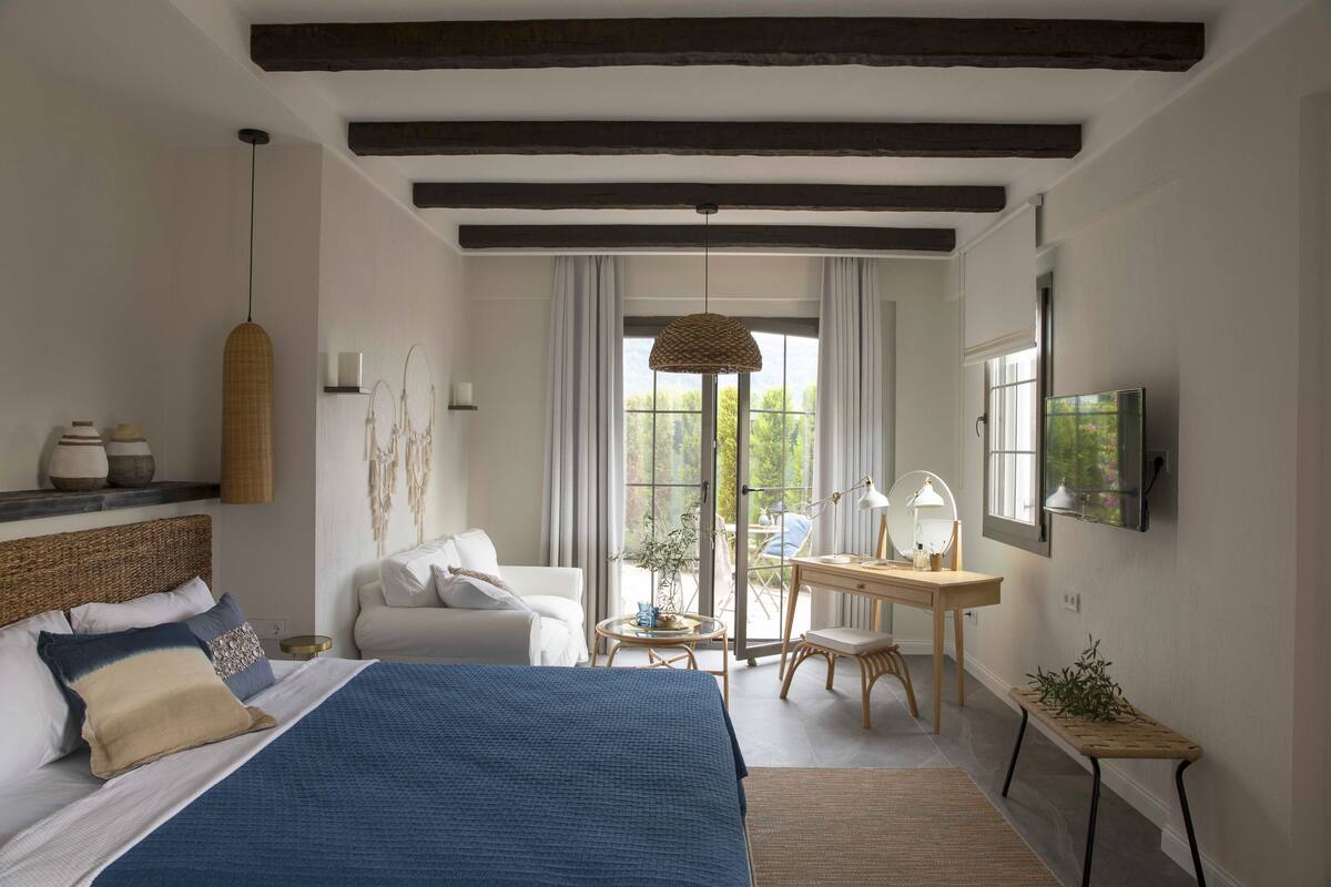 A bedroom with a large bed, a desk, a chair, and a television.