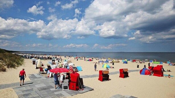 A beach with tents and beach chairs, a boardwalk, and the ocean in the background. - Blockhaus in Trassenheide (Trassenheide)