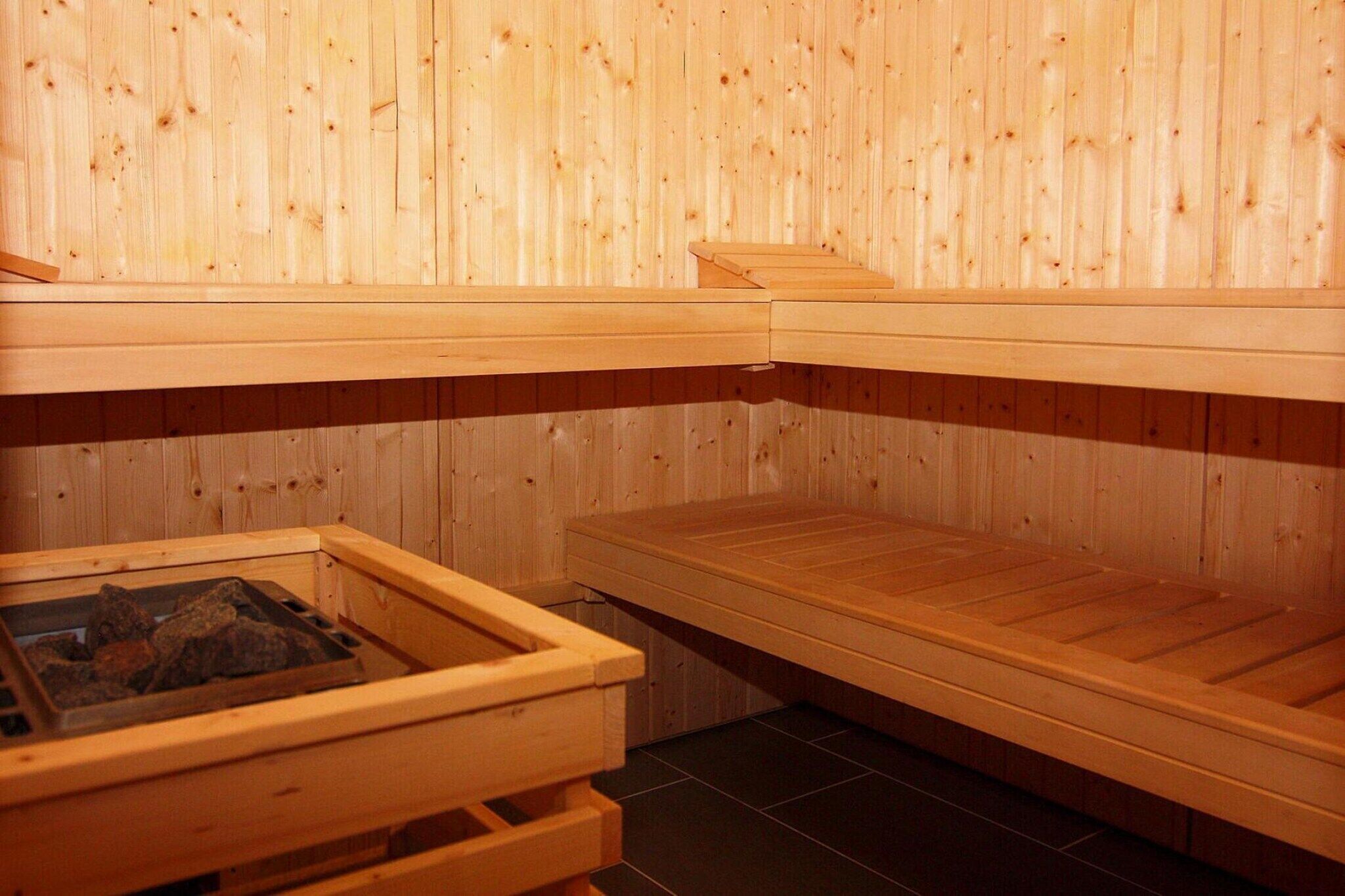 A sauna with wooden benches and a stone heating element.