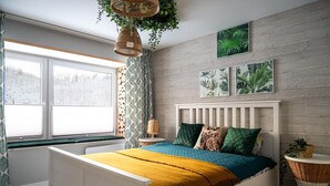 A bedroom with a white bed, a yellow throw blanket, and a view of a snowy landscape through the window.