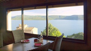 A dining table with chairs and a view of a lake and hills. - Scenic Village Home with Lake Panorama (Sainte-Croix-du-Verdon)