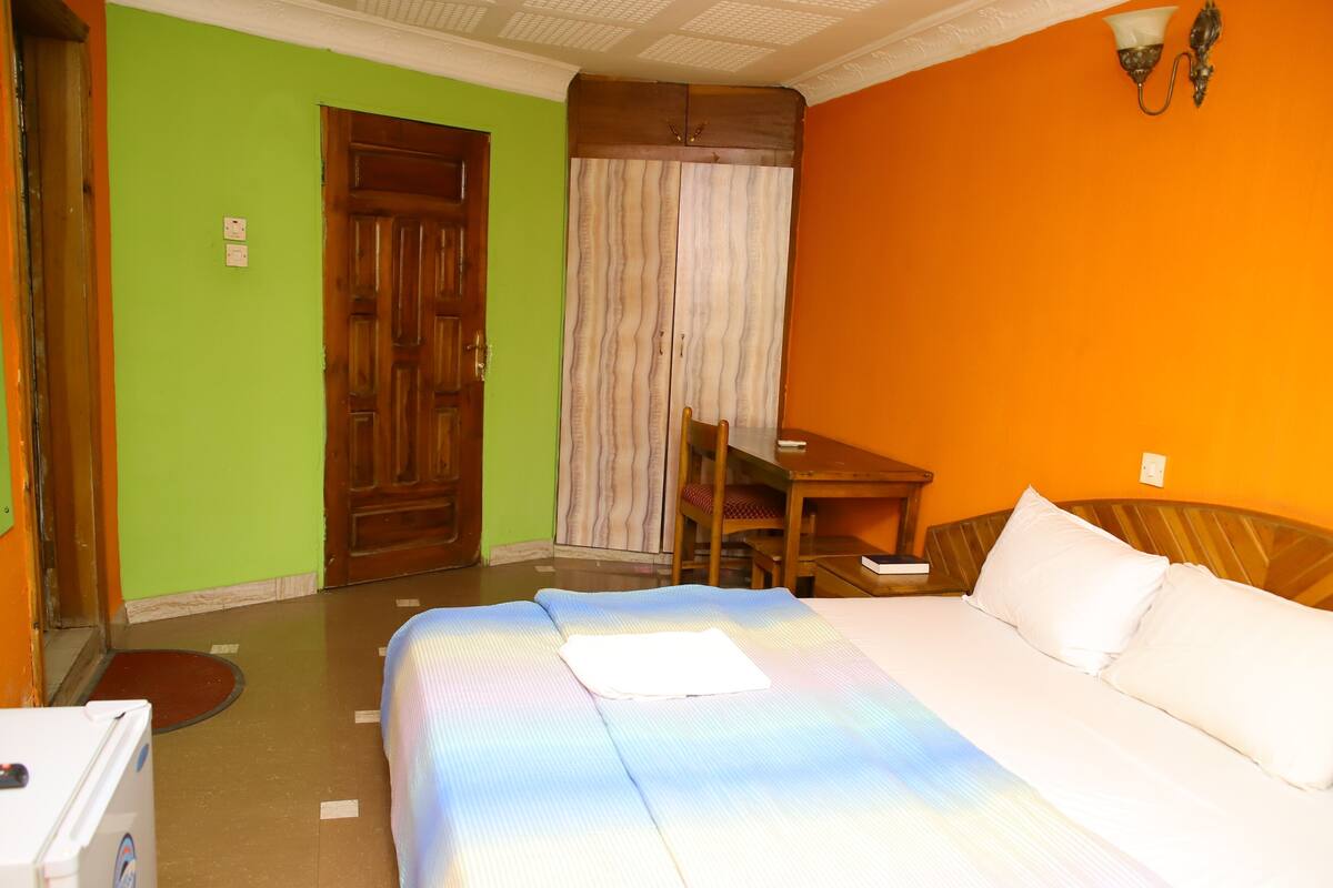 Ein Hotelzimmer mit Bett, Stuhl, Tisch und Tür.