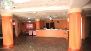 A lobby with marble flooring, orange columns, a reception desk, and a chandelier. - Mokland Hotel and Suites (Lagos)