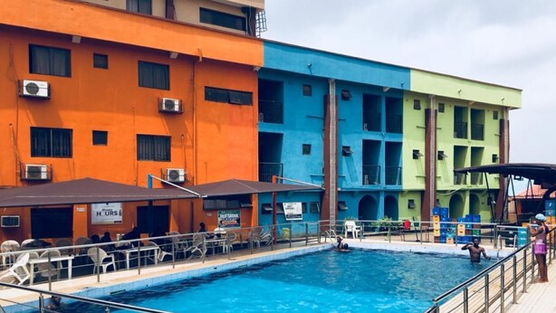 A swimming pool with a tiled deck and metal railings. - Mokland Hotel and Suites (Lagos)