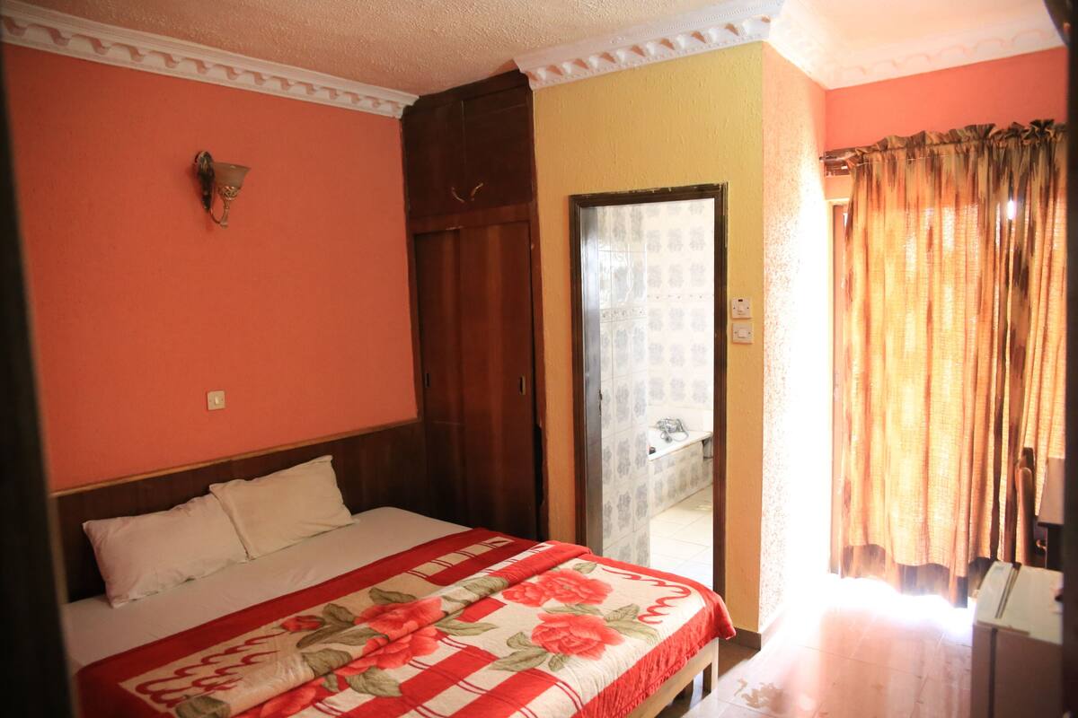 Ein Schlafzimmer mit Bett, Schrank, Spiegel und einer Tür zum Badezimmer.