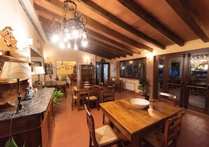 A dining area with wooden tables and chairs, a chandelier, and a view through glass doors. - Agriturismo Sorgituro (Postiglione)
