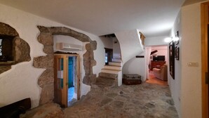 A stone-walled hallway with a staircase leading to another room.