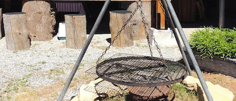 Una silla colgante de metal con sistema de soporte de cadena, rodeada de rocas y una estructura de madera.