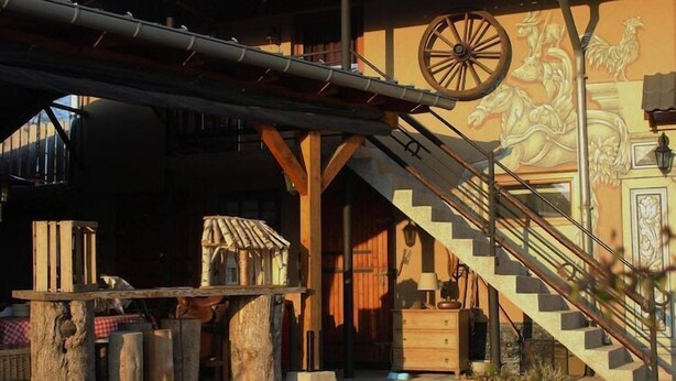 Un edificio rústico con una escalera de madera, una gran mesa de madera y un mural con un caballo y un gallo.