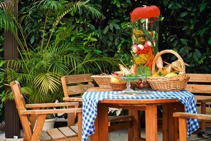 A wooden table with a checkered tablecloth, surrounded by wooden chairs, and filled with baskets of fruits and vegetables.