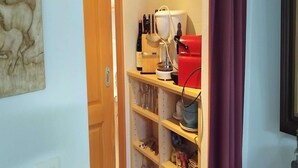 Una cocina con una estantería para vinos, una cafetera y un electrodoméstico rojo en la encimera.