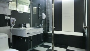 Un baño moderno con suelo a cuadros blanco y negro, inodoro blanco, lavabo con espejo y zona de ducha.