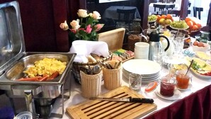 A buffet setup with various food items, utensils, and a cutting board. - Teytz Apartments (Prague)