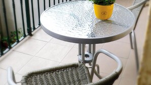 A small outdoor patio with a round glass table, two wicker chairs, and potted plants. - Teytz Apartments (Prague)