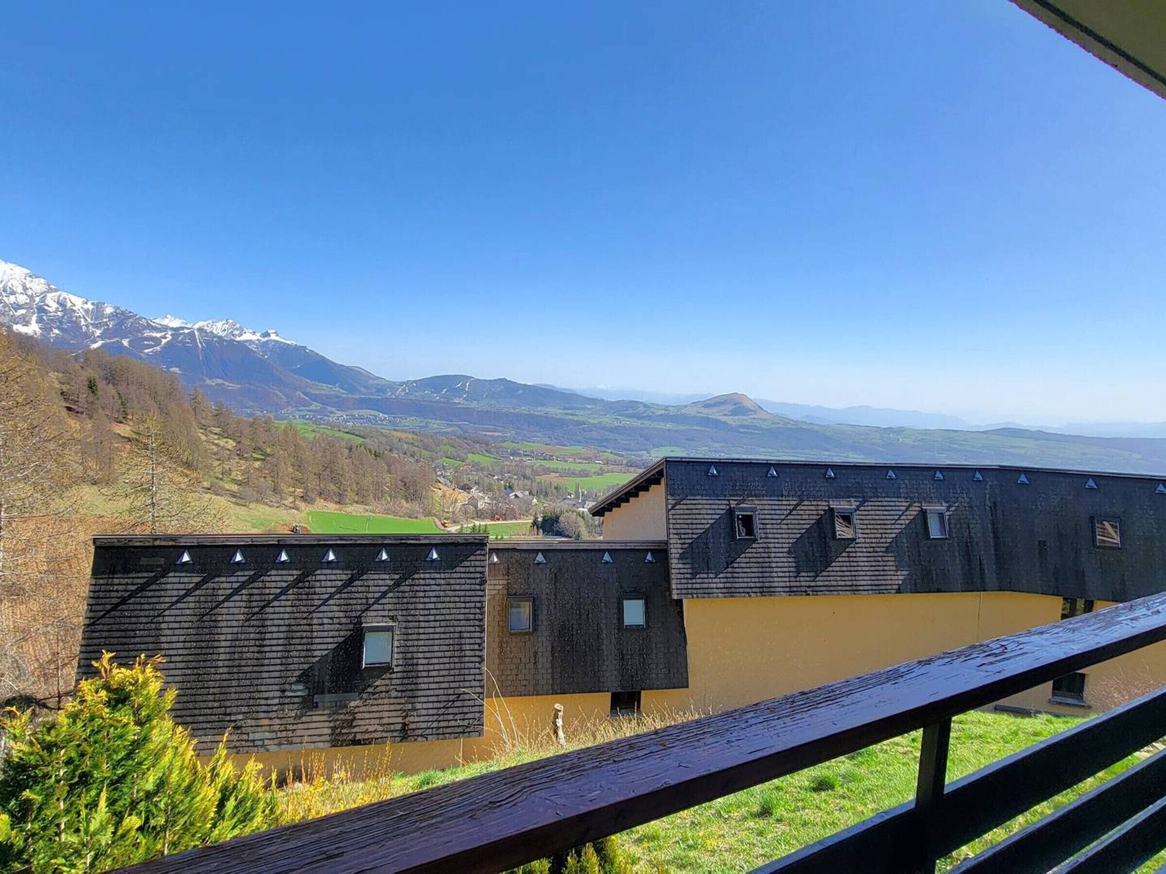 A modern building with a sloped roof and multiple windows, overlooking a mountainous landscape.