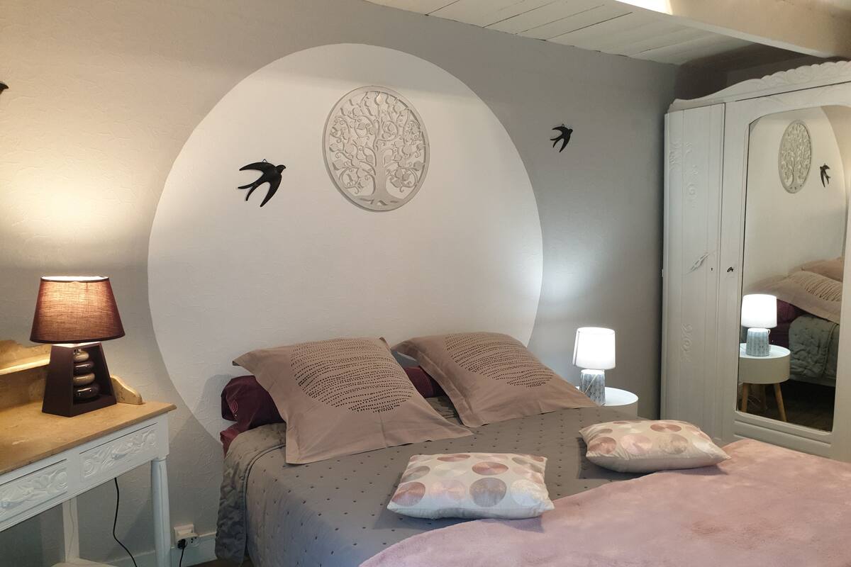 A bedroom with a bed, pillows, a lamp, a dresser, and a mirror.