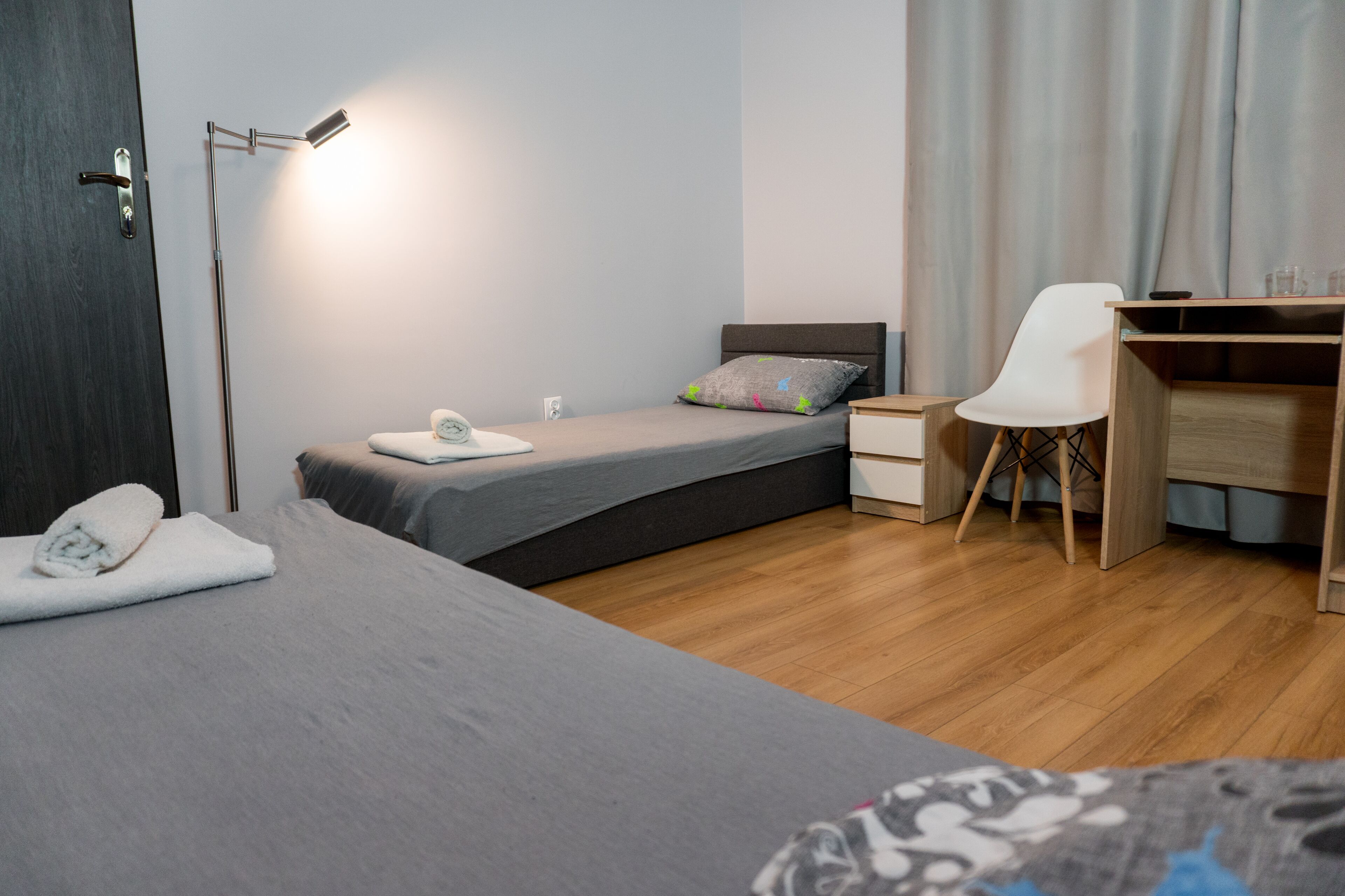 Una moderna camera d'albergo con un letto, un comodino, una scrivania, una sedia e una lampada da terra.