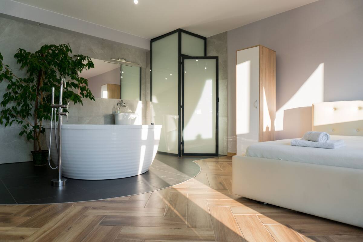 Une chambre moderne avec un grand lit, une baignoire intégrée et une plante en pot.