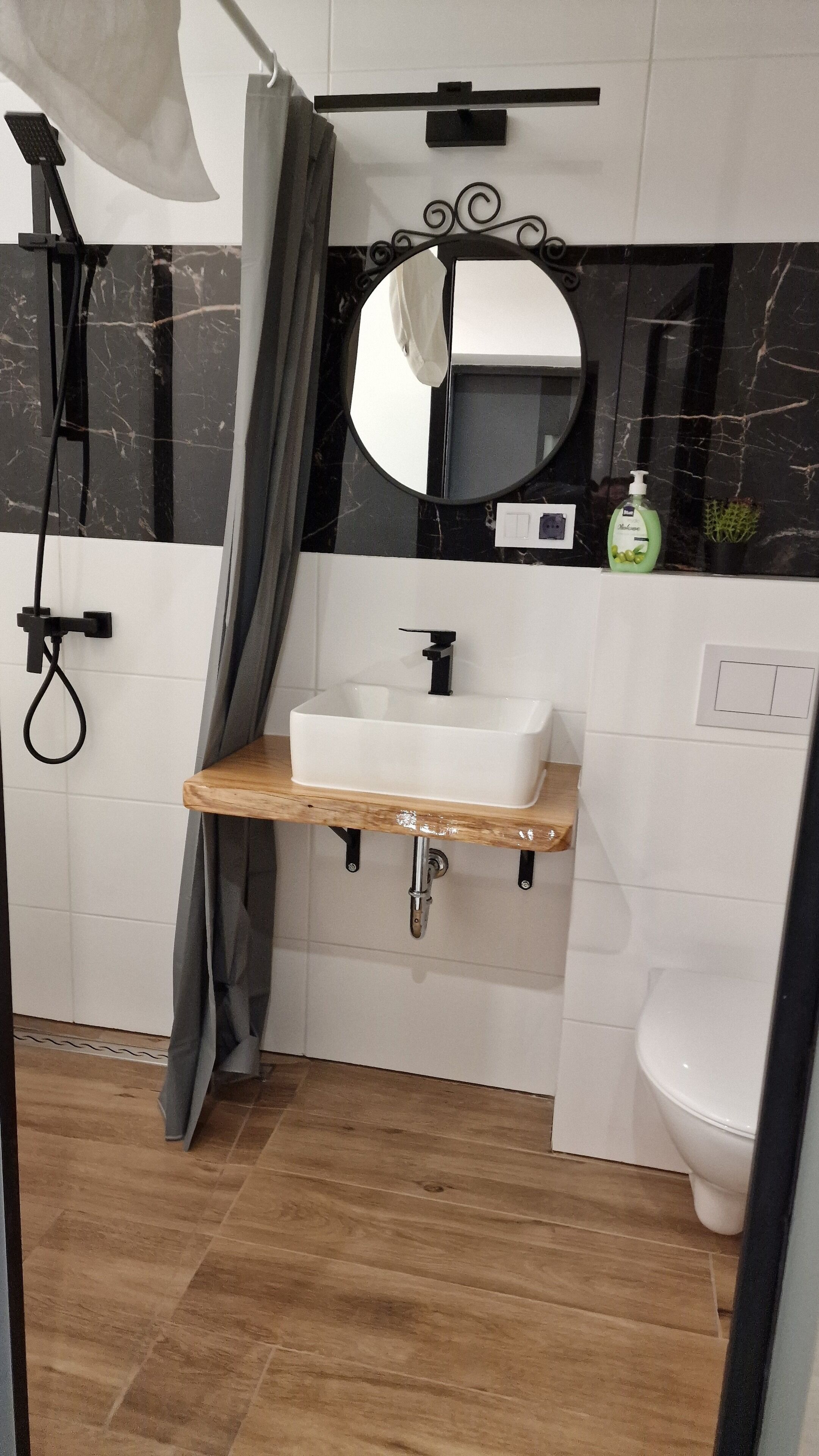 Een badkamer met een wit wastafel, een spiegel, een douche en een toilet.
