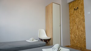 A room with two single beds, a white chair, and a wooden door with a logo. - Pensjonat Lubianka (Starachowice)