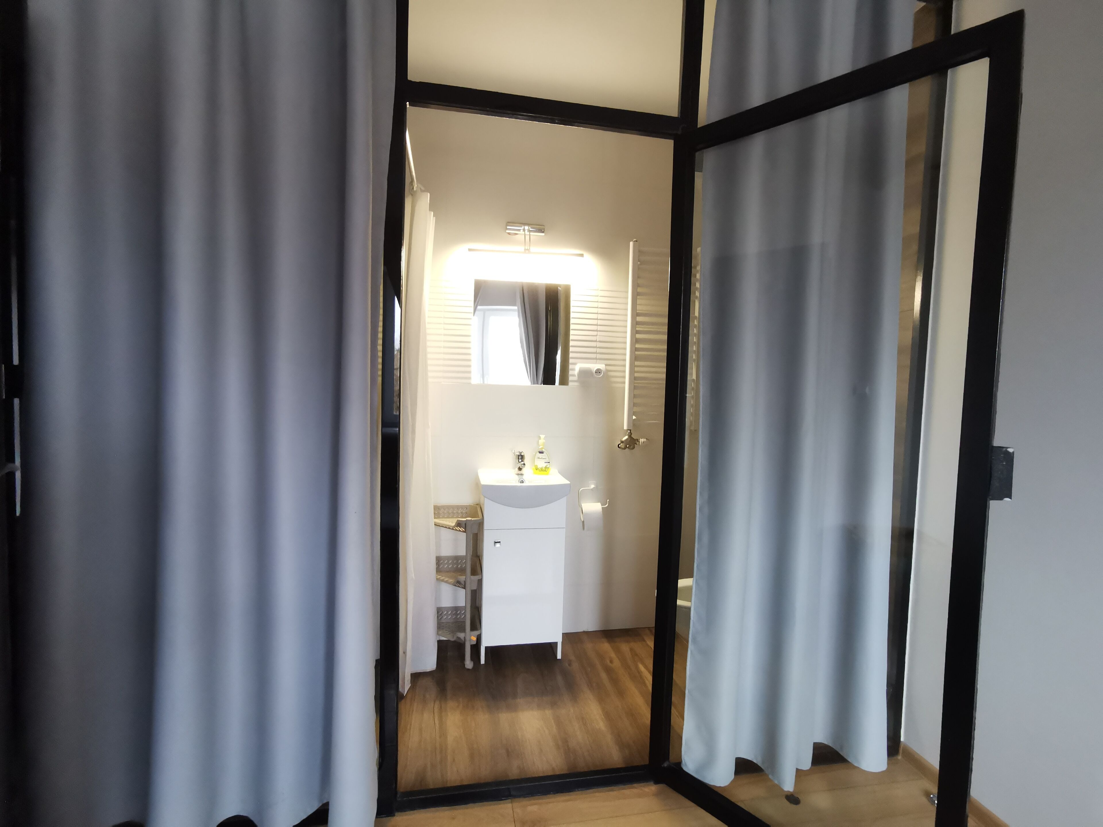 A modern bathroom with a white sink, mirror, and shower area.