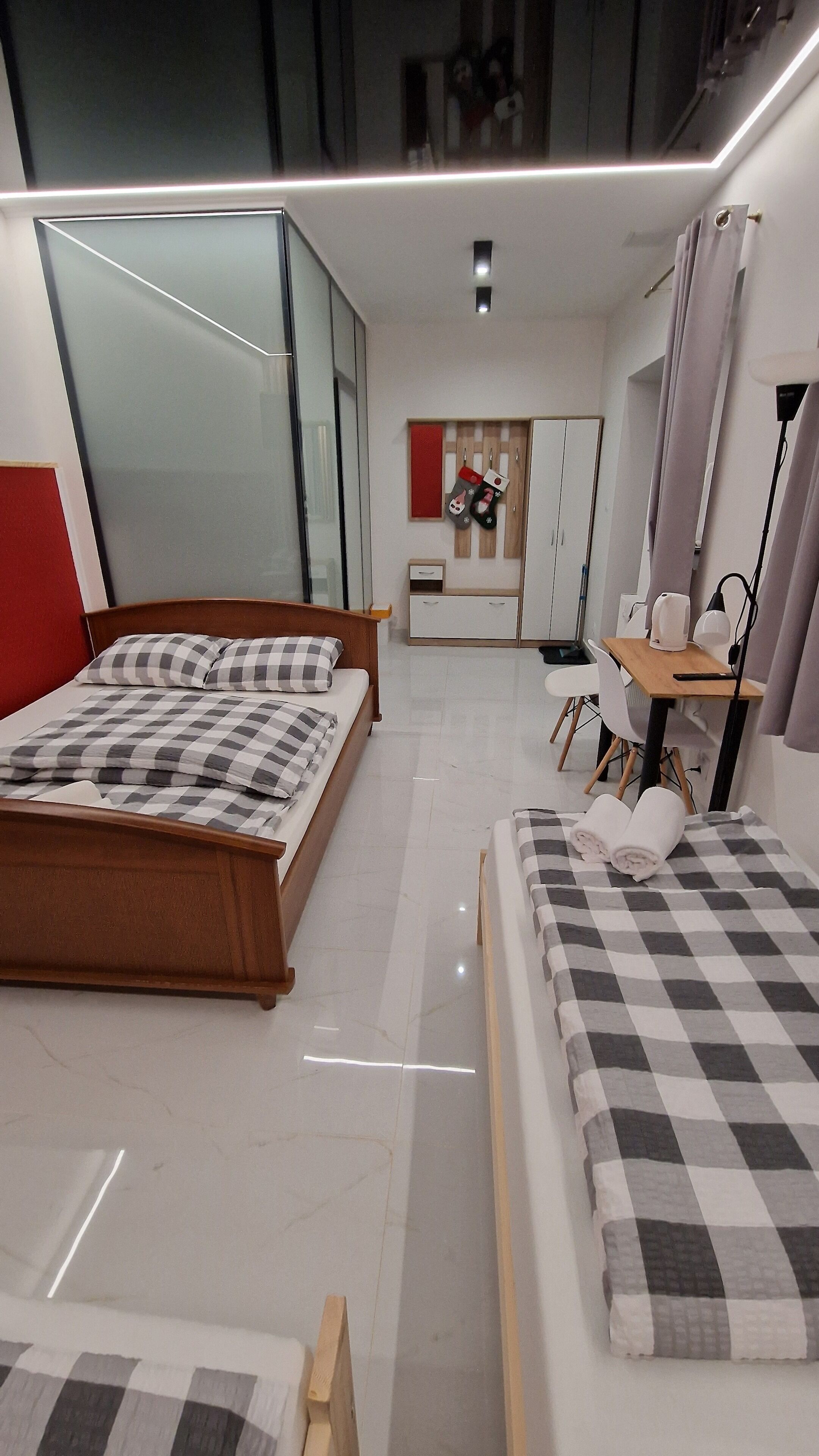Een moderne slaapkamer met een groot bed, een kleiner bed, een bureau en een kledingkast.