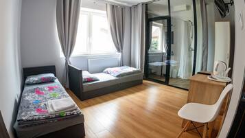 A bedroom with a bed, a desk, and a sliding glass door leading to a shower area.