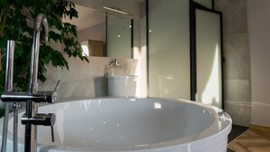 A modern bathroom with a freestanding bathtub, a glass shower enclosure, and a large mirror. - Pensjonat Lubianka (Starachowice)