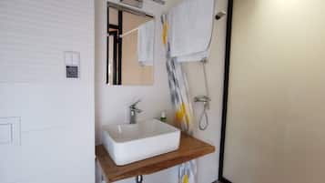 A modern bathroom with a white sink, wooden countertop, and a shower with a towel rack.