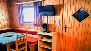 A wooden cabin room with a bed, a desk with a coffee maker, a TV, and a window with curtains. - Chalet in Gaal by Ski Slopes & Alpine Park (Gaal im Murtal)