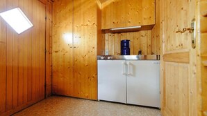 A compact kitchen with wooden walls, a built-in coffee maker, and a white refrigerator. - Chalet in Gaal by Ski Slopes & Alpine Park (Gaal im Murtal)