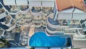 Un hôtel moderne doté de nombreux balcons, d’une piscine centrale et d’espaces de détente en plein air.