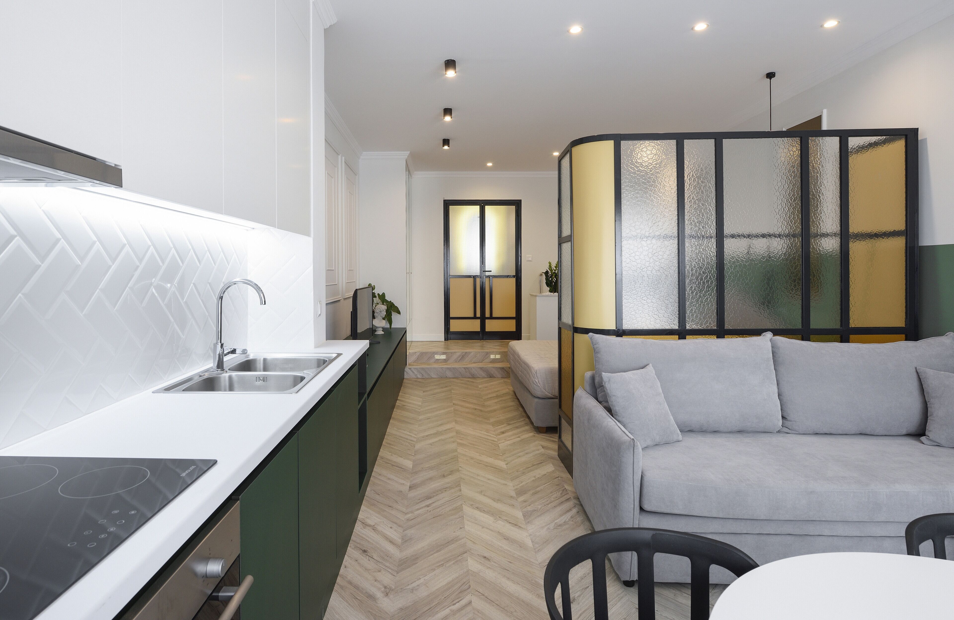 A modern kitchen with a built-in stove, a sink, and a herringbone-patterned floor.