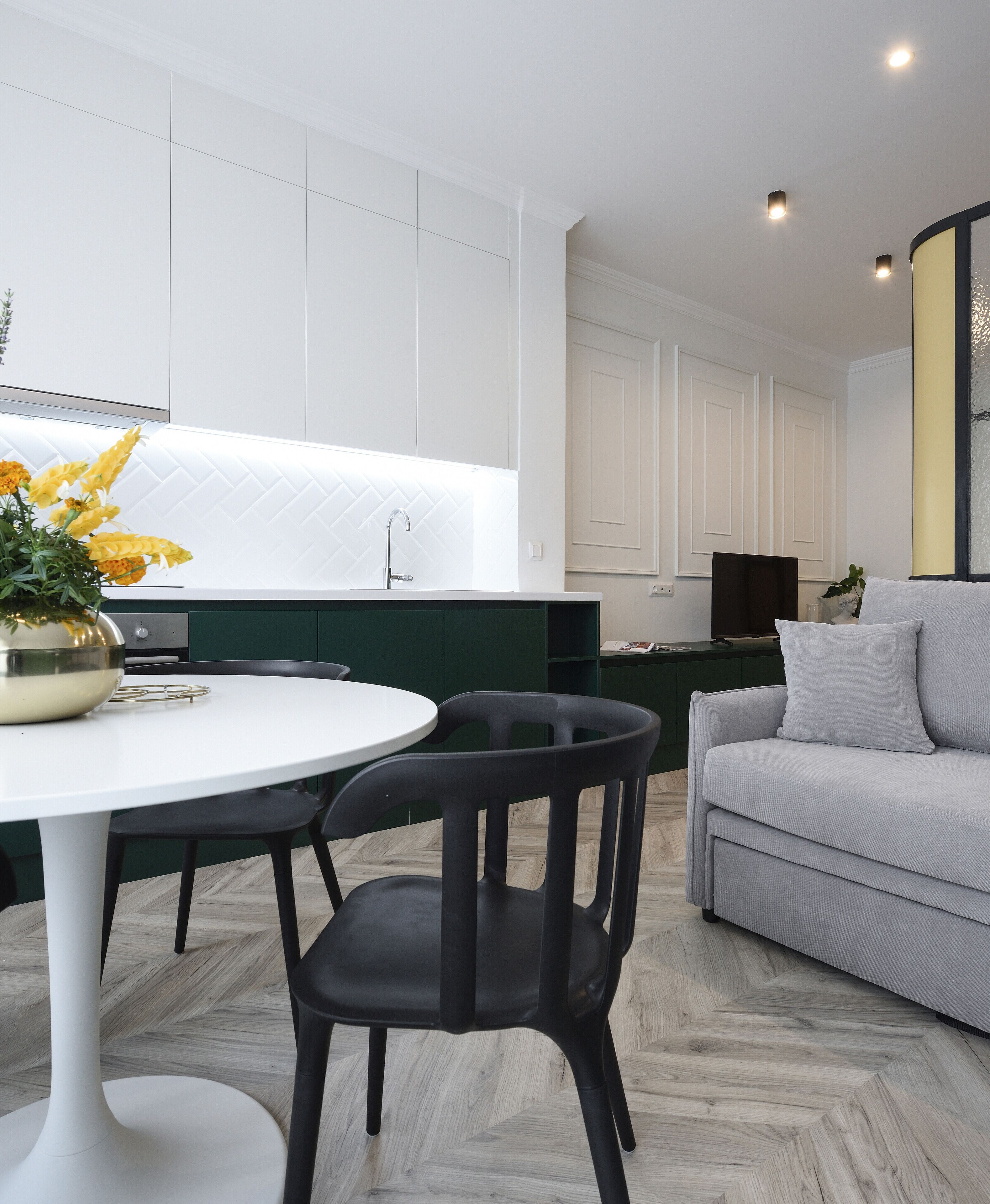 A modern kitchen with white cabinets, a white countertop, and a round dining table with black chairs.