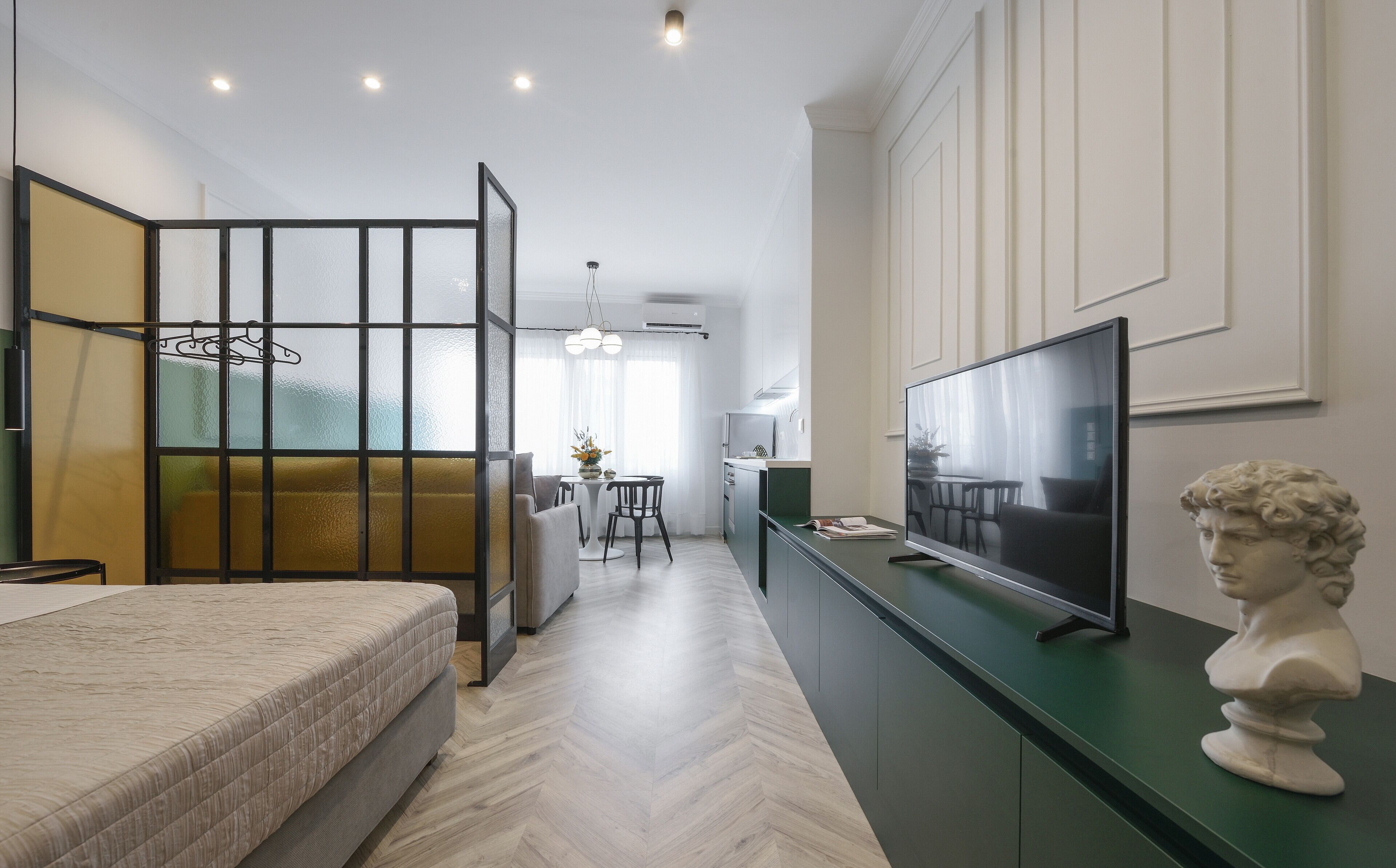 Een moderne, goed verlichte kamer met een bed, een televisie en een borstbeeld.