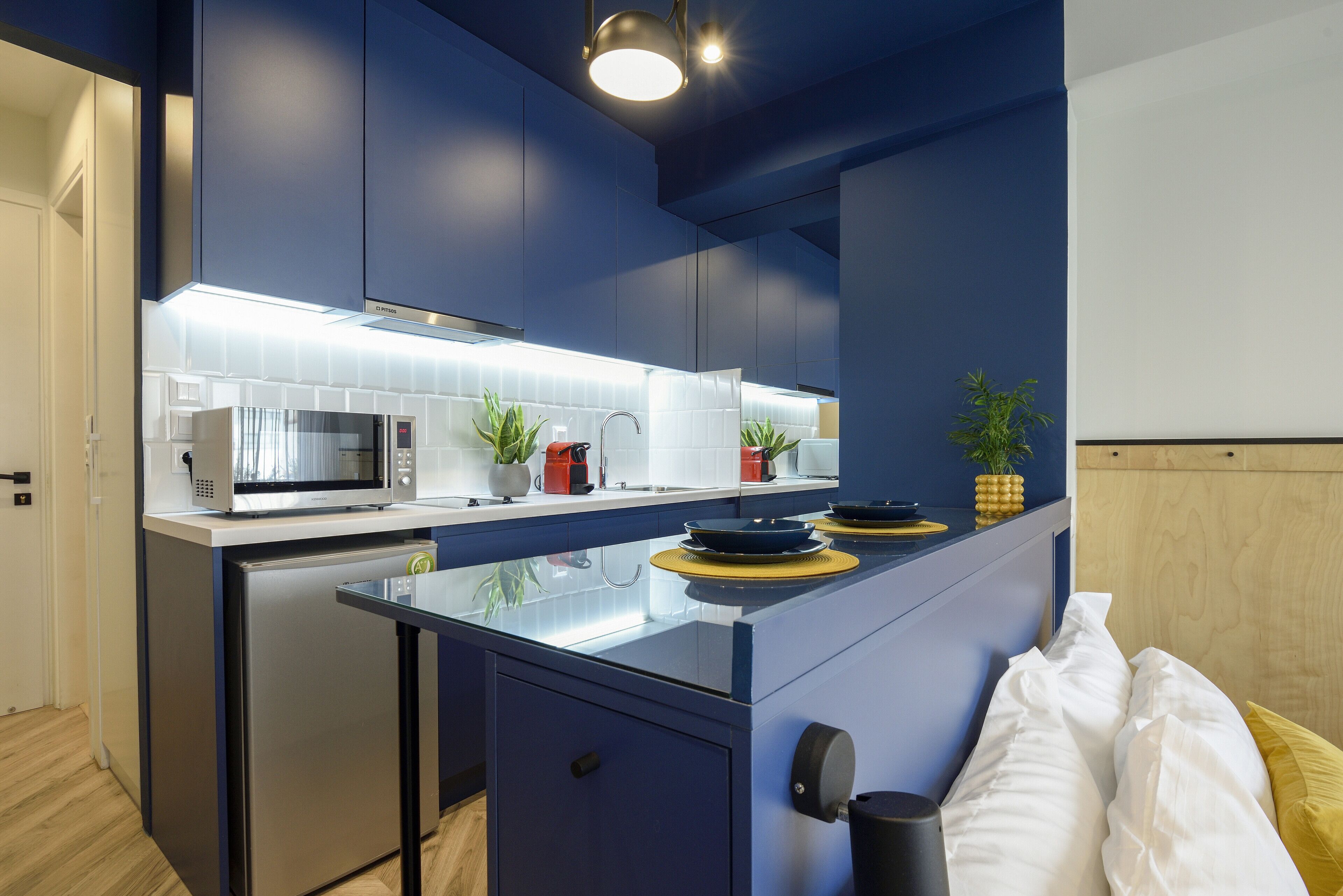 A modern kitchen with a built-in microwave, stove, and sink. There are two potted plants on the counter.