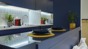 Une cuisine moderne avec un plan de travail bleu foncé, un crédence blanc et des appareils électroménagers en acier inoxydable.