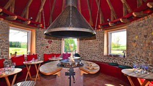 A cozy interior with a central fire feature, stone walls, and red accents. - Holiday Farm in Pfaffenhofen with Indoor Pool (Kindwiller)